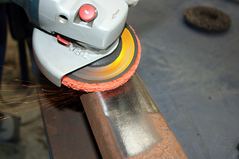 یک سنباده برقی در حال پرداخت سطح فلزی قبل از رنگ کردن فلز زنگ زده